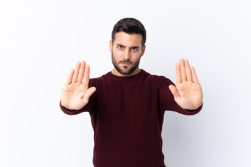 Young handsome man with beard over isolated white background making stop gesture and disappointed