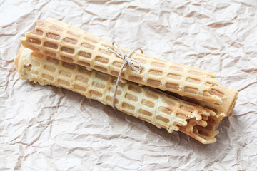 Homemade wafer rolls tied with jute on baking paper background. Close-up photo, space for text.