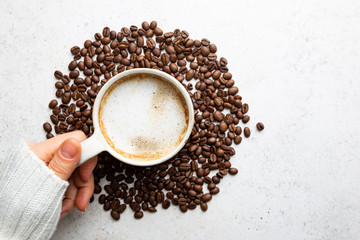 Cup of coffee in womens hand on white background, top view