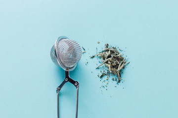 Obraz premium Blue background, strainer and poured a handful of tea Bai Hao Yin Zhen Silver needles, useful properties of tea, raises the immune system, providing effective protection from disease