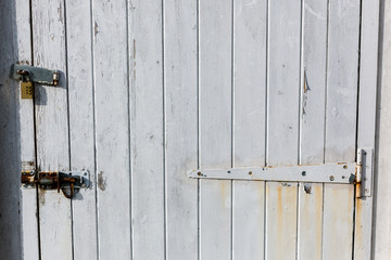 An old wooden door secured by a padlock and deadbolt to stop anyone breaking in and stealing