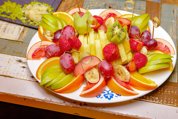 Fruit on a white plate. Sliced fruit on a colorful table