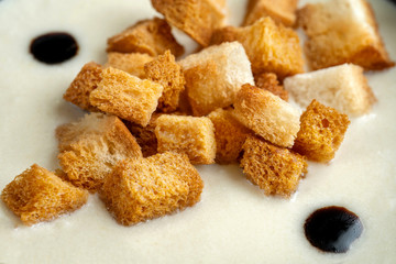 Wheat bread croutons in a white puree soup.