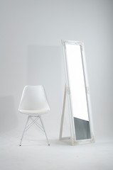 Completely white room with interior items such as a mirror and a chair