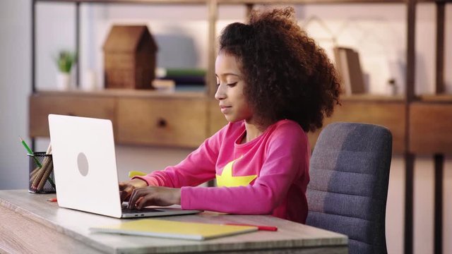 African American girl doing homework on laptop