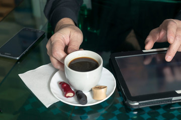 man drinks coffee and uses the Internet in a computer