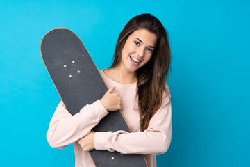 Teenager girl over isolated blue background with a skate with happy expression © luismolinero