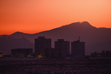 Block of flats silhouette in orange sunrise light. City in the morning