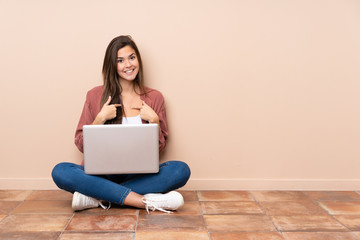 Teenager student girl sitting on the floor with a laptop with surprise facial expression