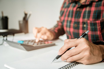 Writing paper on desk, businessman hand using calculator Calculating bonus(Or other compensation) to employees to increase productivity.