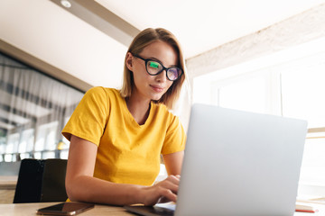 Photo of beautiful young woman working on laptop while sitting