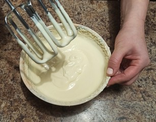 woman hold mixer over bowl with cream