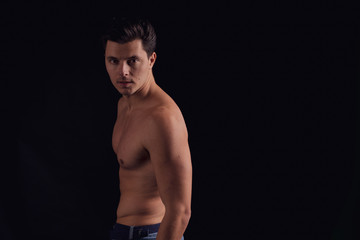 Fototapeta na wymiar barechested guy with a dramatic light in the Studio. unfolds on camera