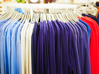 Multi-colored clothes on hangers. Mens clothing. Discount in the store for mens sweaters.