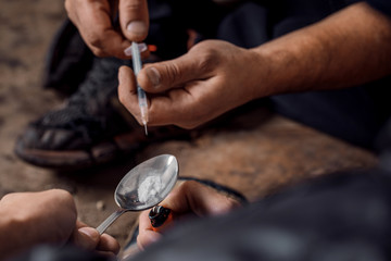 two shabby  men preparing drug injection in slums