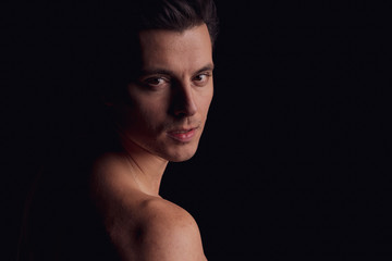 barechested guy with a dramatic light in the Studio.. close-up, looking directly at the camera