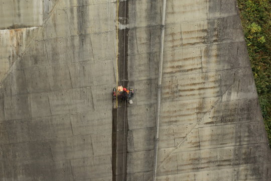 Homme escaladant la paroie d'un barrage