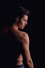 barechested guy with a dramatic light in the Studio. looks aside, the silhouette of the man. close-up