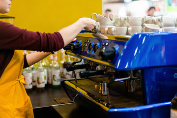 barista with coffee machine in yellow apron