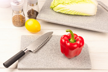 A section of bell pepper with a sharp knife on a cutting board made of artificial stone