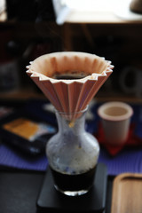 Fototapeta na wymiar Origami filter dripping coffee into a glass carafe. Electronic scale. Alternative manual brewing