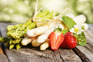 Grüner und weißer Spargel mit Erdbeeren auf Brett, copy space