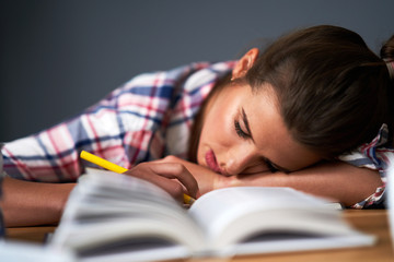 Tired female student learning till late at home