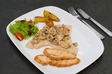 Braised champignons with fish fillet, salad, fried potatoes and croutons