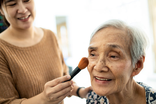 Happy Asian Senior Woman Or Mother Enjoy Makeup On Face, Joyful Female Caregiver Or Daughter Is Helping Old People Makeup,applying Blush To Cheek By Brush, Services,care And Support For The Elderly