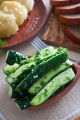 Sliced salted cucumbers with dill and garlic in a wooden bowl, selective focus