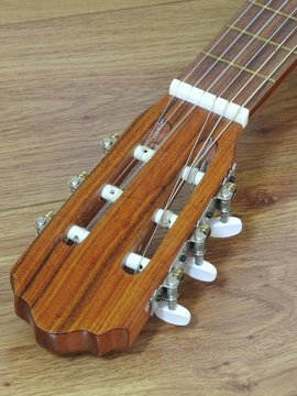 Close-up of an acoustic guitar headstock on a wooden surface. This instrument is widely used in Brazil in samba and choro ensembles.