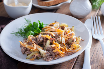 Minced salad of boiled beef and egg pancakes on a white plate, selective focus