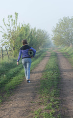 Obraz premium Woman with sleeping pad walking in nature beautiful misty morning in summer space for text back view