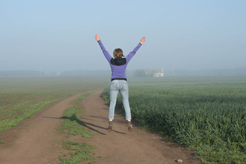 Happy woman traveler jumps among fields  beautiful misty morning