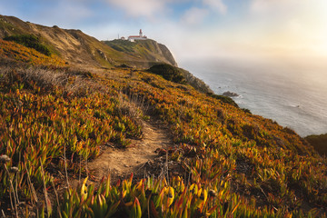 Sintra Portugal. Lighthouse on Cape Roca. Travel and hiking path lit by golden sunset light....