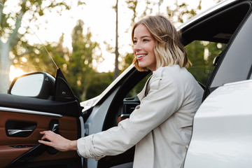 Image of young beautiful businesslike woman sitting in luxury car