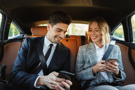 Image of young businesslike man and woman using smartphones in car
