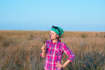 red-haired girl in spend time with pleasure in summer prairie at sunset