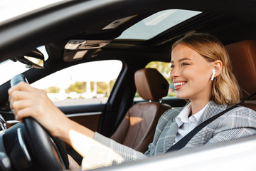 Image of young caucasian successful businesslike woman driving car