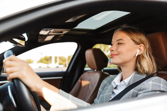 Image of young caucasian successful businesslike woman driving car