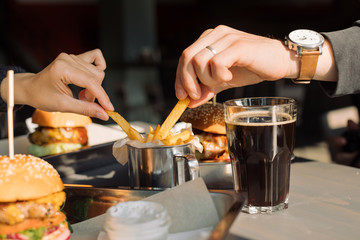 Friends ready to eat French fries and burgers in cafe. Close up. Fast food concept.