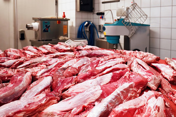 Fresh raw beef meat on the table and meat mincing equipments in the background in a slaughterhouse