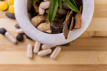 Top view macro shot of herbal pills and tablets arranged with spices on a red stone. Unani medicines concept.