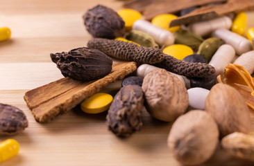 Top view macro shot of herbal pills and tablets arranged with spices on a red stone. Unani medicines concept.