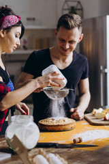 Beautiful photo session of a couple in love. Love game of a guy and a girl while cooking an apple pie.