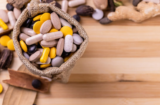 Top view macro shot of herbal pills and tablets arranged with spices on a red stone. Unani medicines concept.