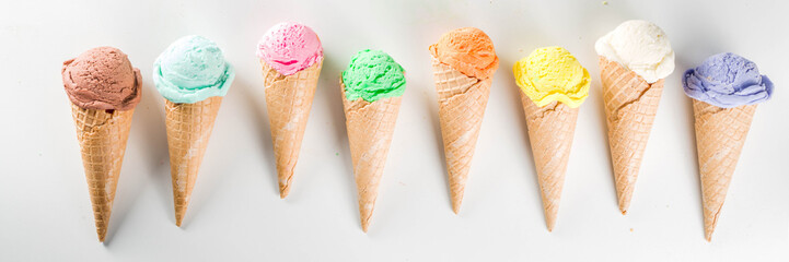 Colorful pastel ice cream with waffle cones, white background, copy space top view