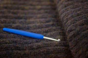 Nahaufnahme von Häkelnadel für Handarbeit, liegt auf gemütlicher, flauschiger handgemachter...