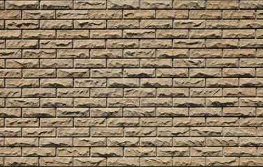 Decorative wall texture, background. Stone cladding of matted stone bricks regular form in soft beige color. The fragment of a new decorative stone laying. The design of cream-colored stylish exterior