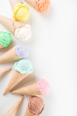 Colorful pastel ice cream with waffle cones, white background, copy space top view